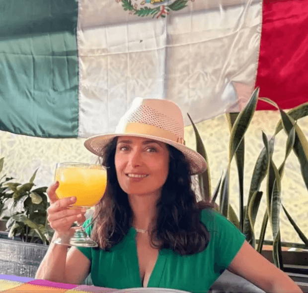 As seen in another image, Salma wore a sheer green dress with a button-detail down the front, topped with a chic straw hat.