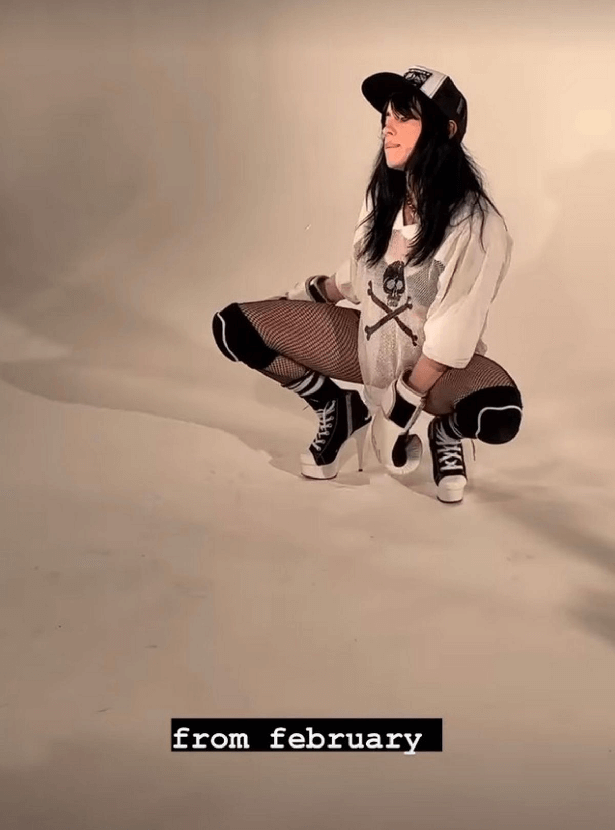 Billie wore fishnet tights, kneepads, black sports socks, and high heels made to look like Converse trainers as she squatted down, holding one boxing glove between each leg.