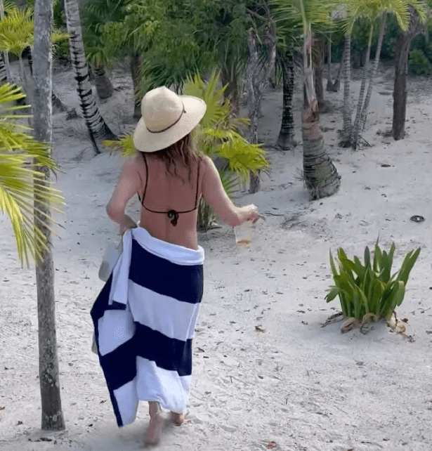 She wore a black and white striped towel around her waist, exposing swathes of her skin with a wide-brimmed straw hat as well as dark sunglasses.
