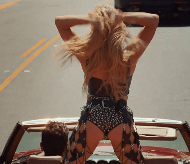 While driving down Hollywood Boulevard in a red car, Sweeney wore her iconic blonde locks in a loose, voluminous blow dry as she mouthed along to the lyrics in a black leather corset covered in silver accents.