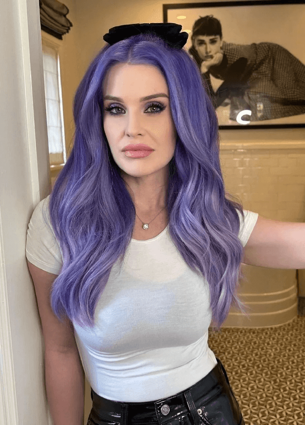 Taking a picture in her bathroom doorway, Kelly Osbourne let her vibrant lilac hair down as she smouldered for the camera in a skintight white t-shirt and leather trousers.