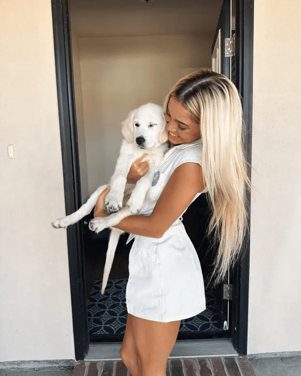 Dunne's latest viral photo shows her cradling her dog in a white dress and revealing knee-high boots to complete the daring look.
