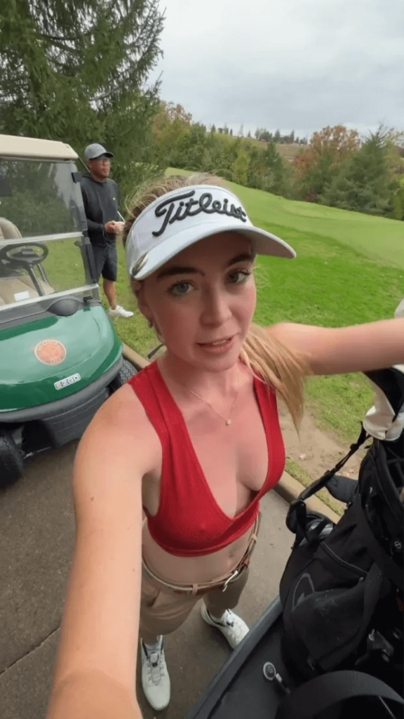 She paired the low-cut top with chinos and a white hat for her rainy round of golf, showing off her bust on the greens.