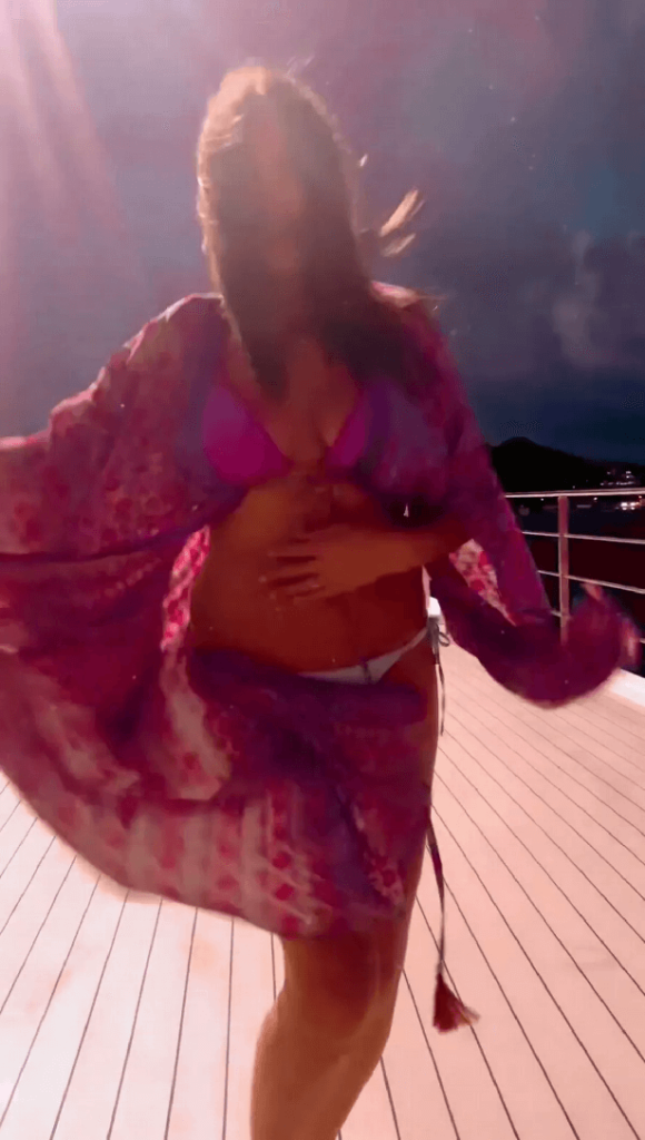 A plunging pink and white bikini risks a wardrobe malfunction as Lisa Snowdon dances on yacht