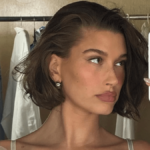 As Hailey Bieber poses before a messy clothes display, she bares her gorgeous abs in only white lingerie