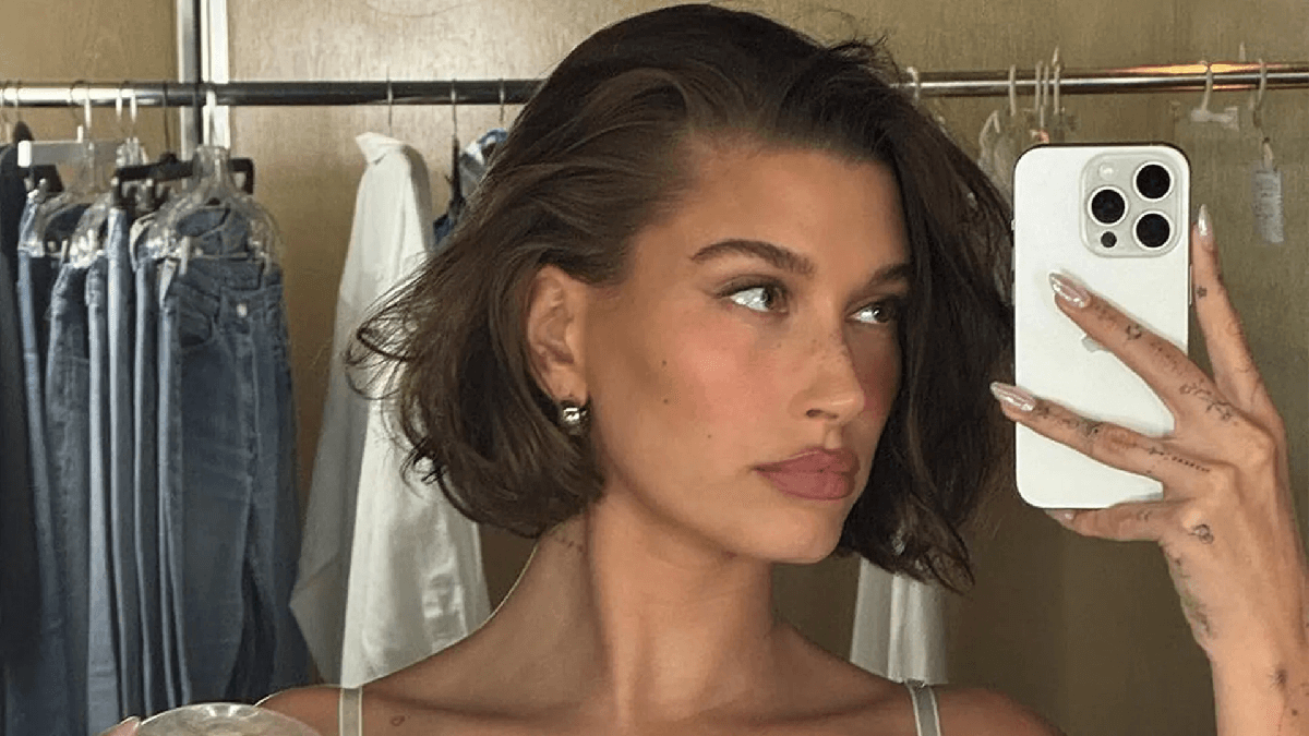 When Hailey Bieber poses before a messy clothes display, she bares her gorgeous abs in only white lingerie