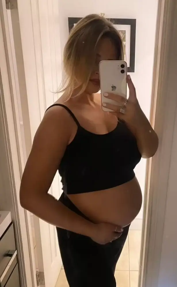 Wearing a black cropped top and maxi skirt, Emily displayed her baby bump in an Instagram selfie shared Friday (January 12).
