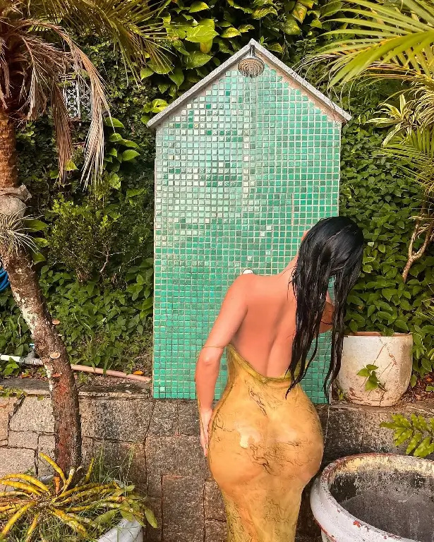 Her hands run through her hair as she observes the beautiful sunset in other images, while in the last one she takes a shower while wearing a mosaic outfit.