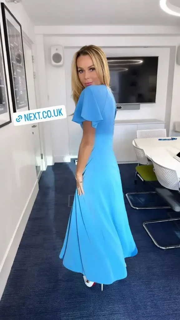 Amanda Holden shows off her cleavage in a blue dress with tight-fitting shoulders and a plunging neckline