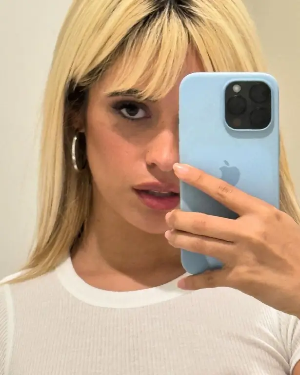 A second shot showed her holding her baby blue iPhone up to the mirror in a nearly see-through white top, zooming in on her face.