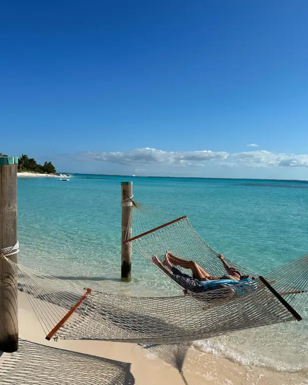 A second photo shows Kourtney tanning in a tiny bikini while Travis shows off his tattoos in shorts as the couple relaxes in a net hammock on the beach.