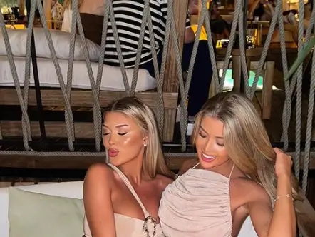 As Eve Gale and Jess Gale pose together in a bar, they are dazzled in satin outfits for their 25th birthdays