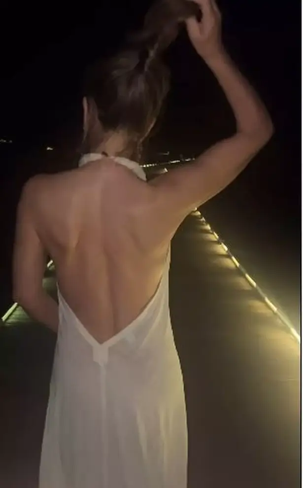 With a dramatic open back and halter neck, she showed off her slim figure and ample cleavage during her midnight coastal walk.