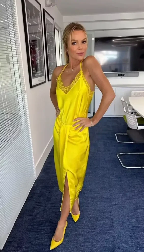 While strutting around the office, Amanda Holden flashed almost her fans while wearing a silk yellow top and clingy skirt. 