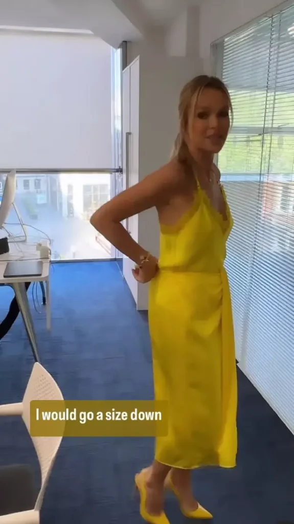 In a silk yellow top and clingy skirt, Amanda Holden poses braless while fans are distracted by her outfit