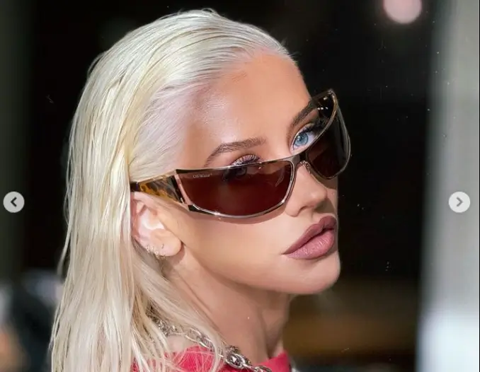 Christina Aguilera models a baggy T-shirt and booty shorts paired with fishnet leggings as she sits on a bar in Las Vegas