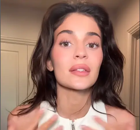 Kylie Jenner appears to be posing on a plastic-wrapped couch as she promoted her new white coat