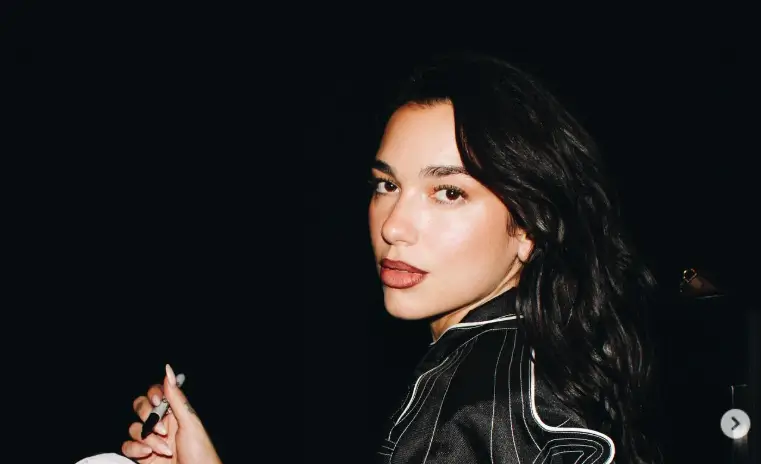 Dua Lipa turns up the heat in an oversized racer jacket and mini leopard print shorts, flaunting her toned legs