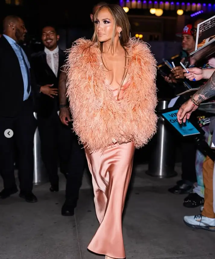 Braless Jennifer Lopez suffers a wardrobe malfunction in a plunging peach gown with feathered sleeves