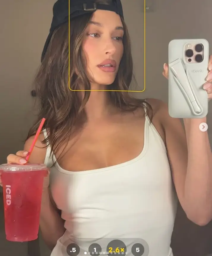 The initial image captures her holding a red iced beverage, adorned in a white tank top and a black cap, worn in a distinctive manner.
